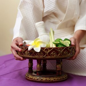 Asian woman holding salt scrub for massage at spa.